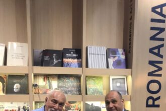Amr Yehia and Varujan Vosganian seated at the Romanian Pavilion, holding a bilingual poetry anthology, during the Cairo International Book Fair.