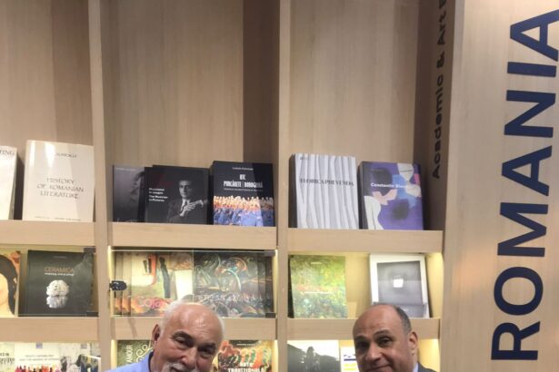 Amr Yehia and Varujan Vosganian seated at the Romanian Pavilion, holding a bilingual poetry anthology, during the Cairo International Book Fair.