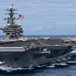 Portavion american al Marinei SUA navigând în larg, cu aeronave militare pe punte, simbol al strategiei de descurajare și proiecție de forță a Statelor Unite.