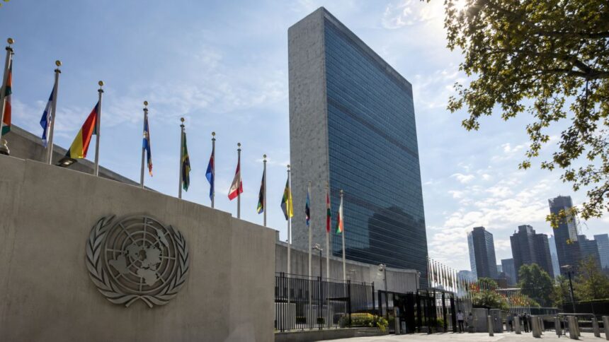 Sediul Organizației Națiunilor Unite din New York, cu sigla ONU și steagurile statelor membre.